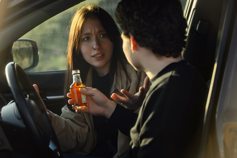 a woman holding a bottle of alcohol in a car