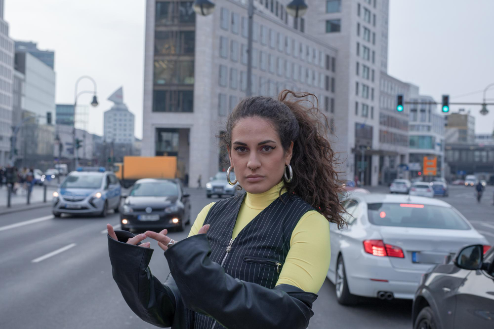 a woman standing on a street with cars in the background